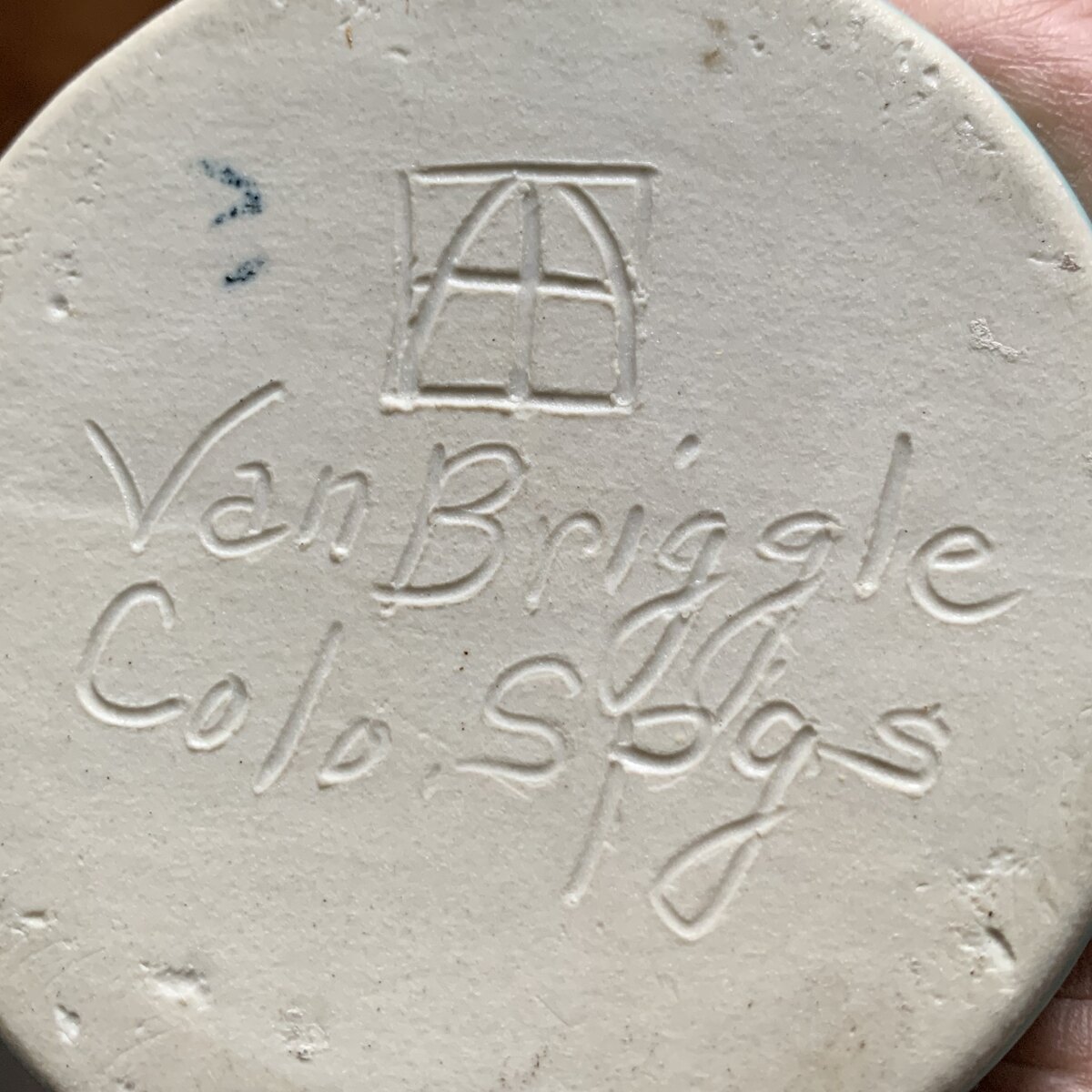 Boxed AA monogram with script Van Briggle and Colo Spgs on a white clay bottom, with a blue painted glazer's mark beside the monogram