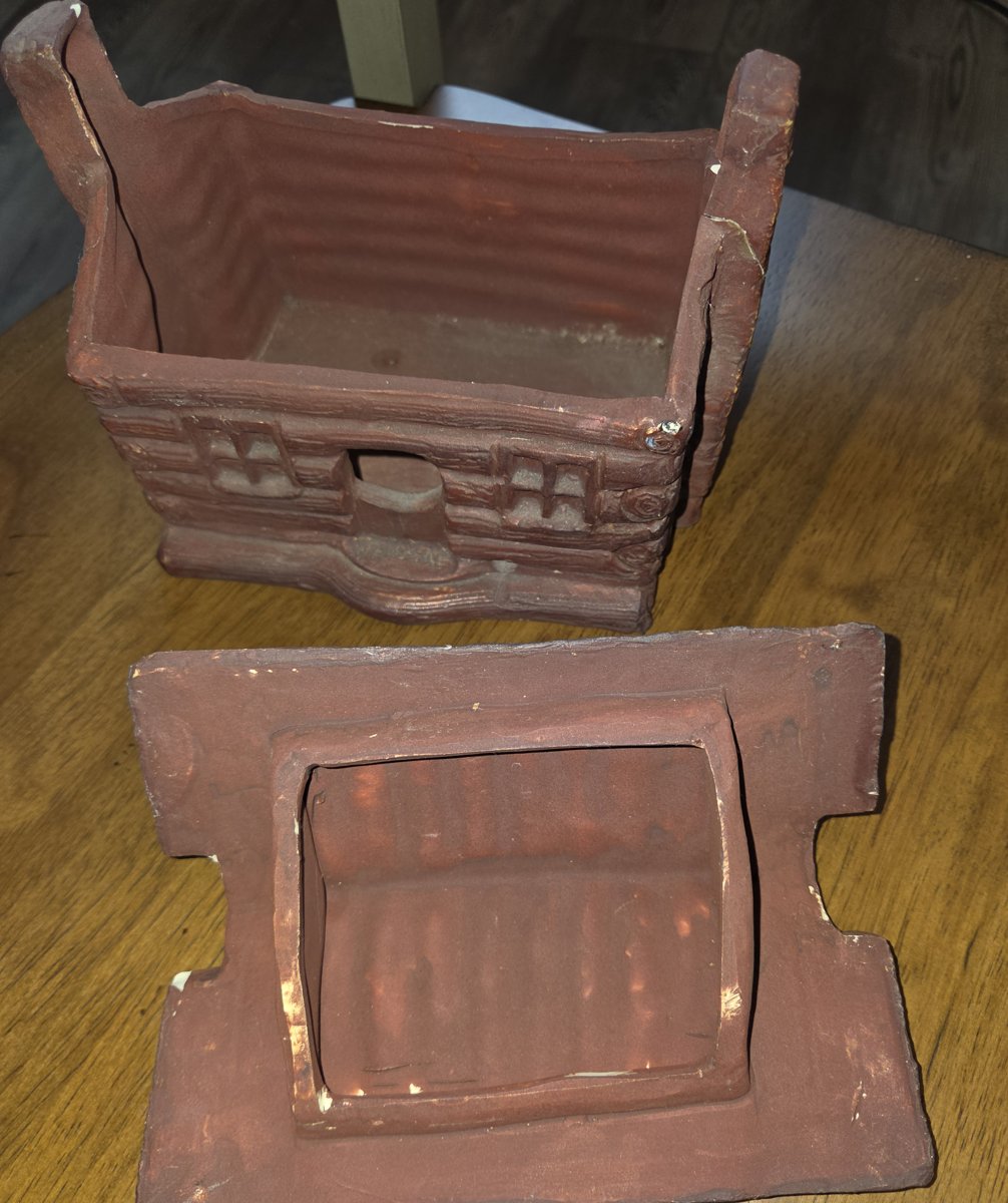 The same log cabin incense burner with its roof off, showing the open doorway, two front windows, the glazed interior and the collar on the underside of the roof